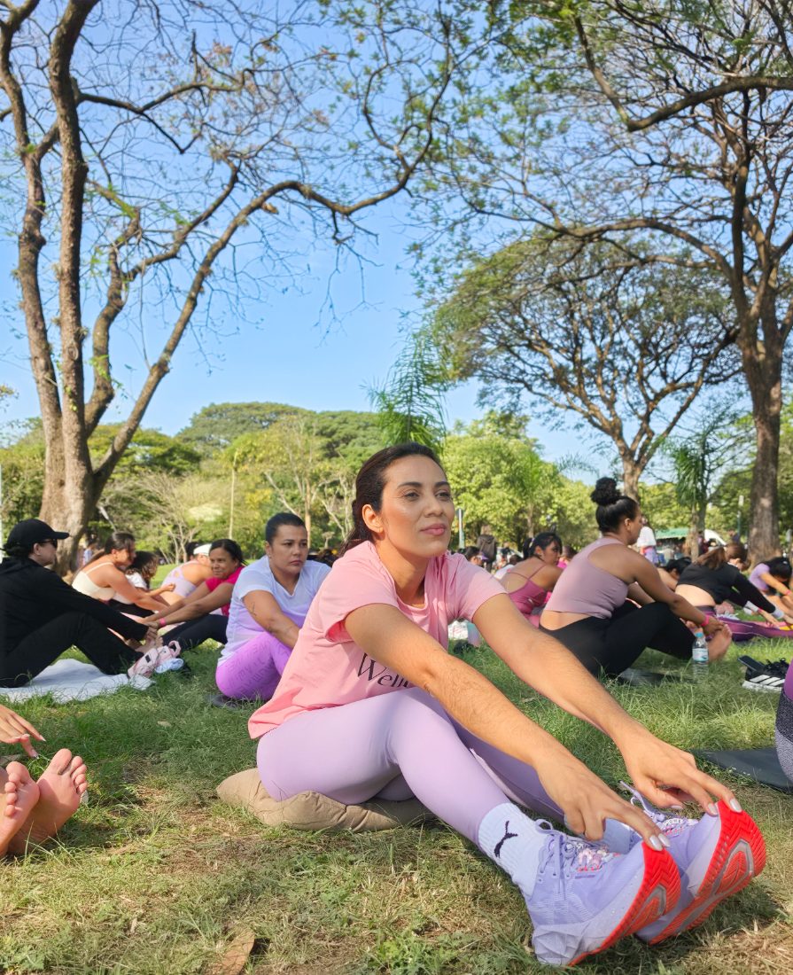 Participante alongando durante a prática de yoga ao ar livre no gramado do parque