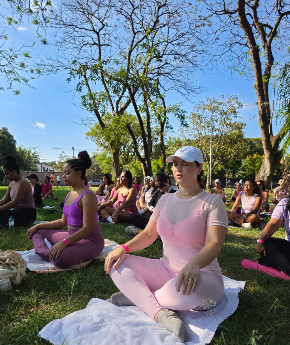 Mulher em meditação, de olhos fechados, durante a prática de yoga no parque
